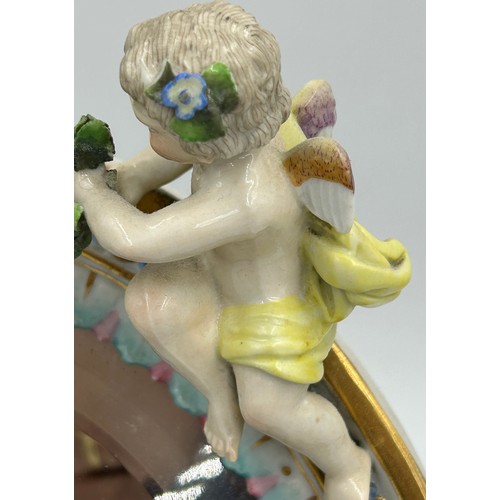 1233 - A Continental porcelain vanity easel mirror with applied cherub and floral decoration and bevelled g... 