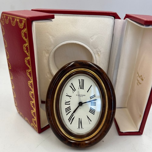 1001 - A Cartier Paris travel alarm clock in original red leather presentation case. 9cm x 7cm.