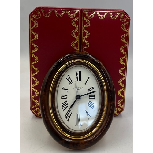 1001 - A Cartier Paris travel alarm clock in original red leather presentation case. 9cm x 7cm.