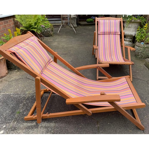 27 - A pair of hardwood steamer deck chairs in candy striped covering with cushion headrest. Approximatel... 