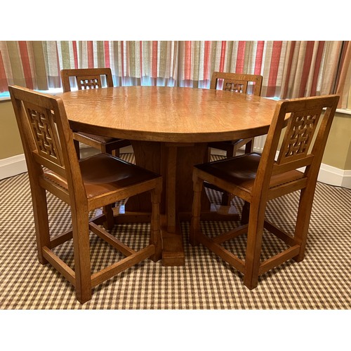 140 - A circular oak dining table with adzed top 128cm d x 73.5cm h together with four lattice backed dini... 