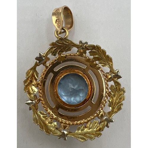 602 - A 18 carat yellow gold circular pendant with leaf decoration and set with a central pale blue stone.... 