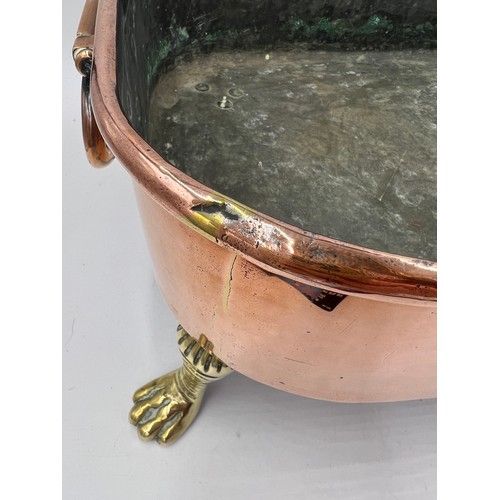 969 - A 19thC copper pan raised on four lions paw feet with drop handles. 45cm l x 32cm w x 22cm h.