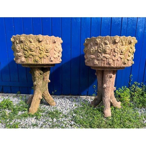 239 - A pair of reconstituted stone faux wood planters with floral decoration. Height 70cm. Diameter 45cm.