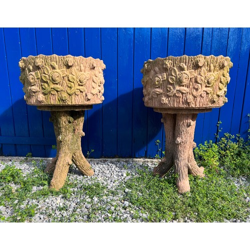 239 - A pair of reconstituted stone faux wood planters with floral decoration. Height 70cm. Diameter 45cm.