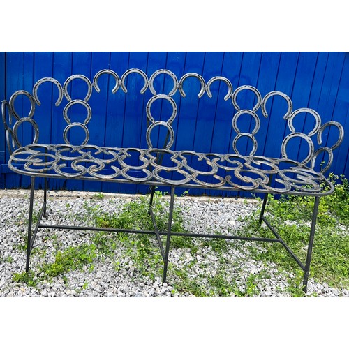 208 - A wrought and forged three seater garden bench formed by an arrangement of horseshoes. 163cm wide.