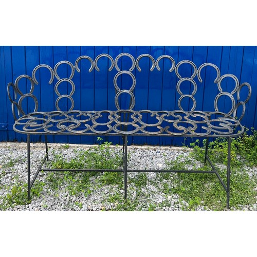 208 - A wrought and forged three seater garden bench formed by an arrangement of horseshoes. 163cm wide.