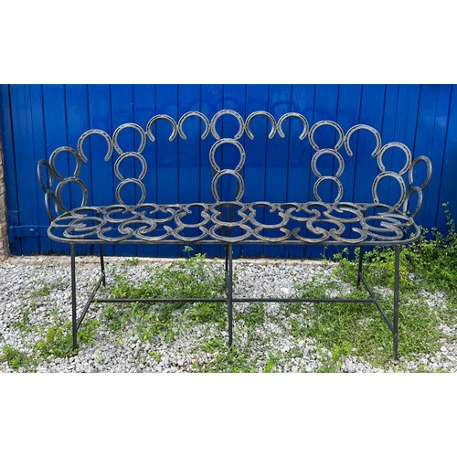 208 - A wrought and forged three seater garden bench formed by an arrangement of horseshoes. 163cm wide.