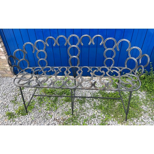 208 - A wrought and forged three seater garden bench formed by an arrangement of horseshoes. 163cm wide.