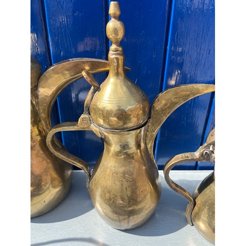 933 - Brassware to include three matching middle eastern early brass dallah coffee pots of different sizes... 