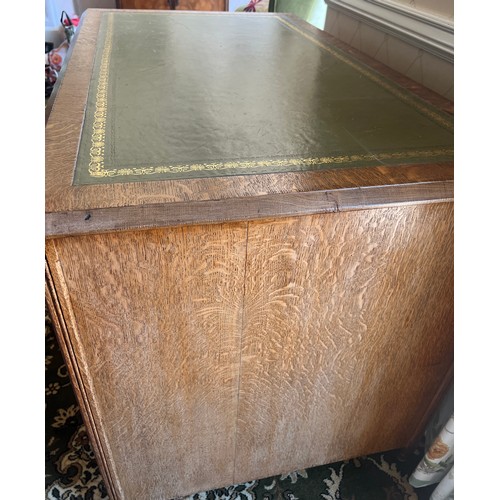 34 - A 19thC oak desk with tooled green leather top and brass drop handles. 115cm w x 68cm d x 76cm h.