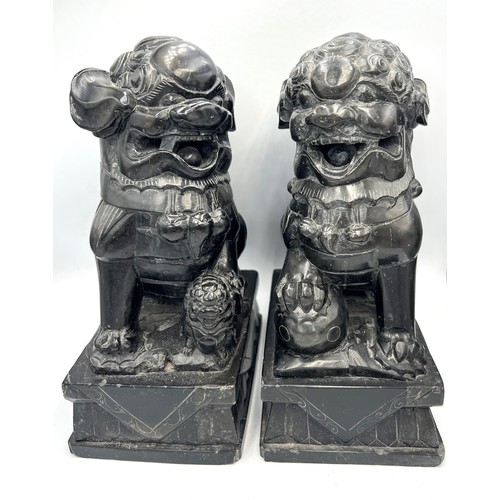 1013 - A pair of black stone foo dogs. 24cm h.