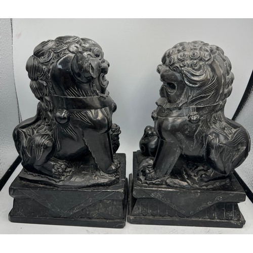 1013 - A pair of black stone foo dogs. 24cm h.