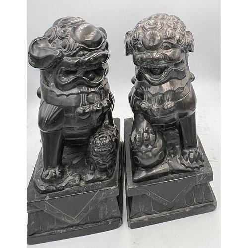 1013 - A pair of black stone foo dogs. 24cm h.