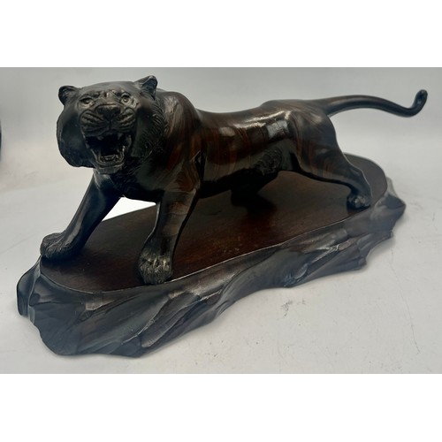 1040 - Japanese bronze tiger on wooden base. 23cm l. Signed to underside.