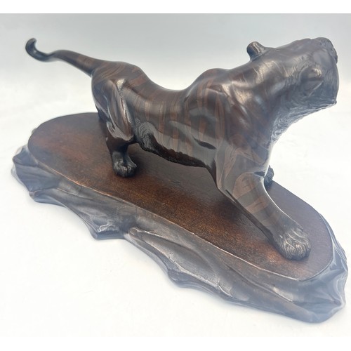 1040 - Japanese bronze tiger on wooden base. 23cm l. Signed to underside.