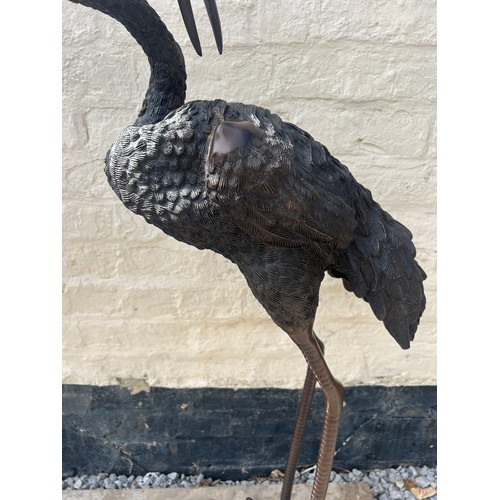 1052 - A pair of Japanese bronze cranes on later marble base. Height 132cm.