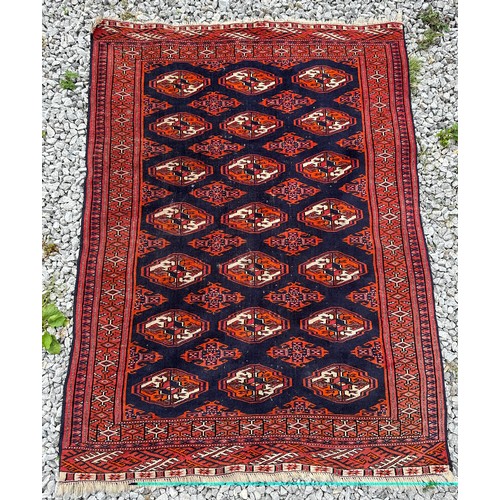 1289 - A 20thC hand knotted floor rug, red ground with blue geometric design and tassels. 140 x 104cm.