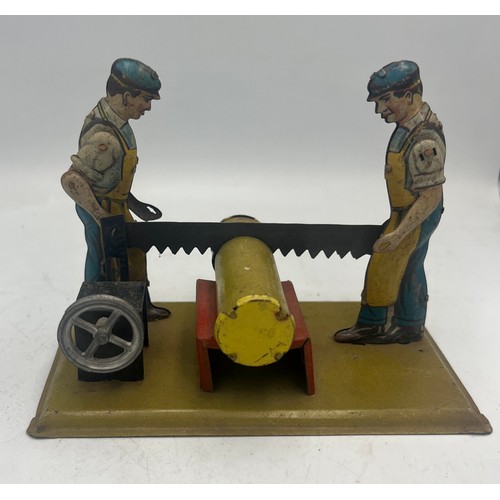 1292 - A vintage toy with men sawing a log. 14cm x 7.5cm.