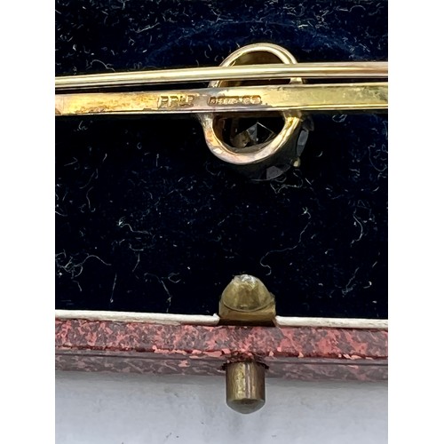 693 - A nine carat gold bar brooch set with red stone in a fitted presentation case. Weight 3.8gm.