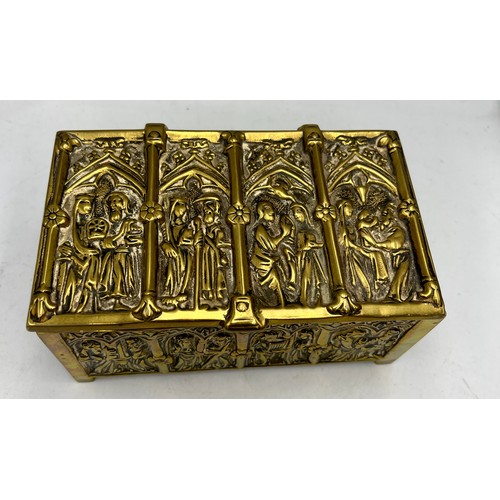 1071 - A brass wood lined casket depicting religious scenes. 15cm x 9 cm x 7cm h together with a tiny Buddh... 