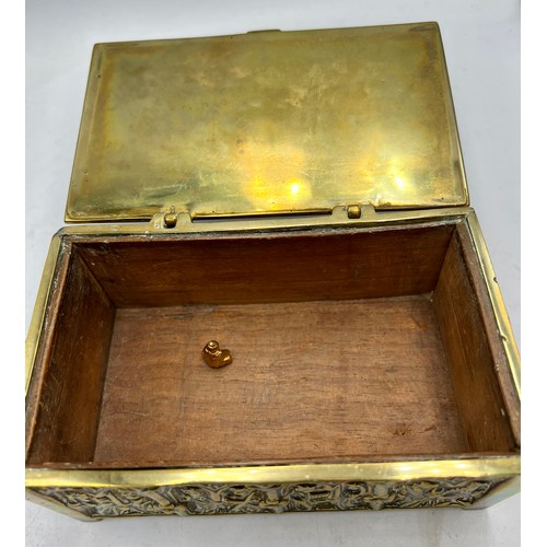 1071 - A brass wood lined casket depicting religious scenes. 15cm x 9 cm x 7cm h together with a tiny Buddh... 