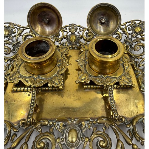 1074 - An ornate early 20thC brass double inkwell with pen stand. 34 x 27cm.