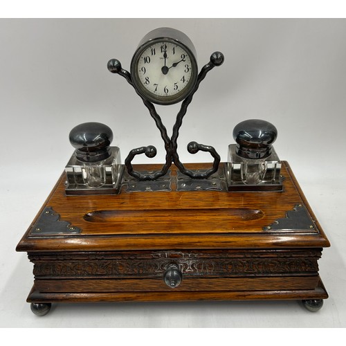 1389 - An oak desk stand with two glass inkwells,  pen trough,  drawer to front and Salvest clock to centre... 