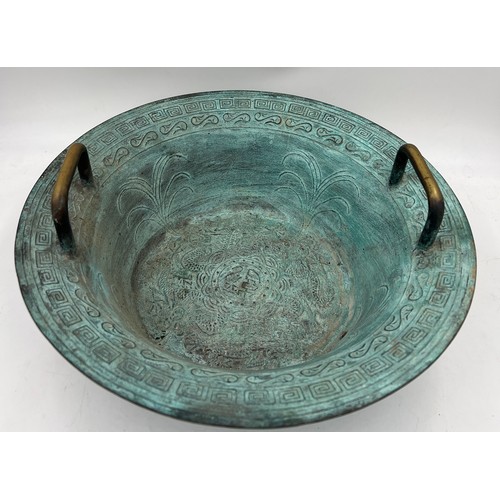 1006 - A twin handled metal bowl with decoration to interior. 40cm d.