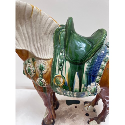 1054 - Two 20thC ceramic Tang horses. The larger coloured glazed horse with large chip to base, 63cm h x 59... 