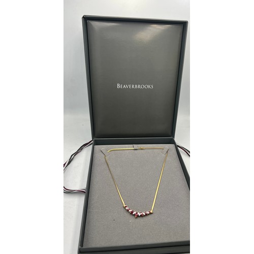 647 - A diamond and ruby necklace on an 18 carat gold chain. Weight 10.3gm. Length 38cm. In original prese... 