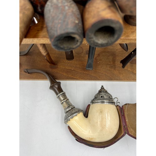 1351 - Wooden pipe rack and various pipes, some with silver mounts, to include a 19thC meerschaum pipe with... 