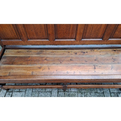 121 - A 19thC oak panel backed settle. 110 h x 184 w x 65cm d.