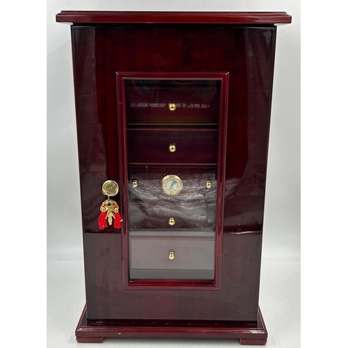 1356 - A lacquered wood humidor cabinet with a glazed door enclosing seven cigar trays and a hygrometer con... 