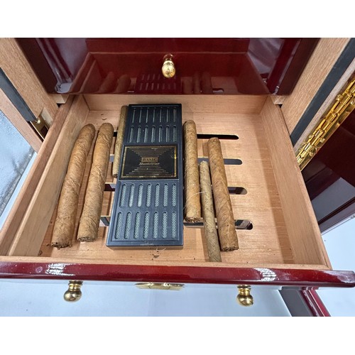 1356 - A lacquered wood humidor cabinet with a glazed door enclosing seven cigar trays and a hygrometer con... 