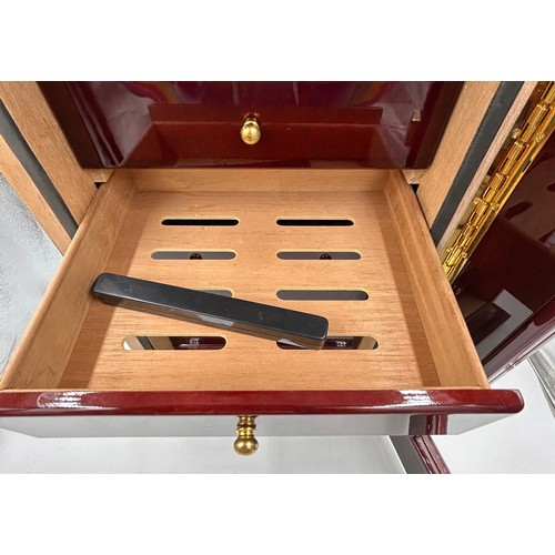 1356 - A lacquered wood humidor cabinet with a glazed door enclosing seven cigar trays and a hygrometer con... 