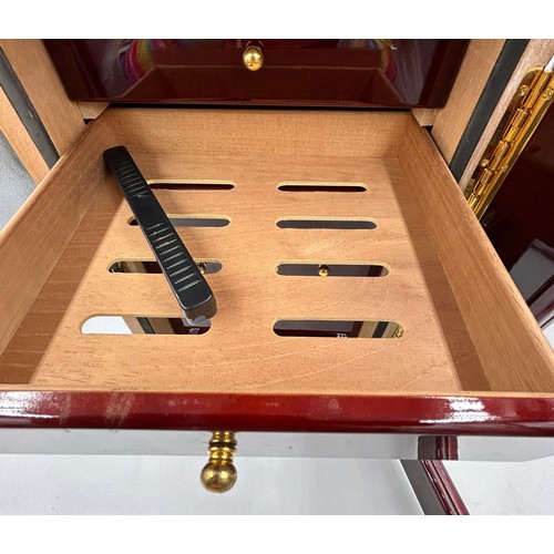 1356 - A lacquered wood humidor cabinet with a glazed door enclosing seven cigar trays and a hygrometer con... 