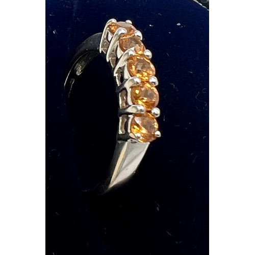 561 - A 9 carat gold gem set ring set with five orange stones. Size N. Weight 2.9gm.