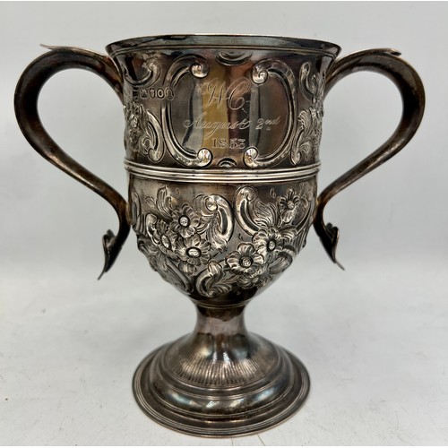 936 - A hallmarked twin handled silver cup with embossed decoration. Later decoration and inscription. Lon... 