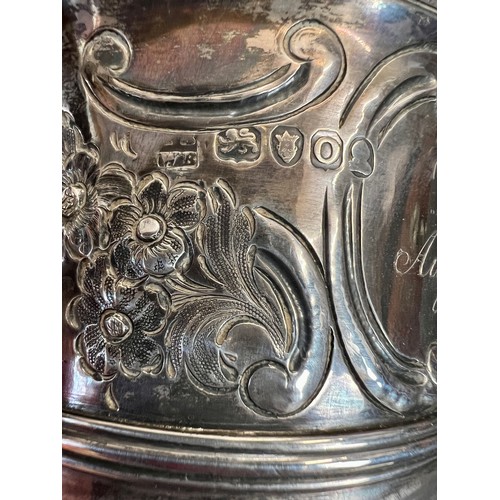 936 - A hallmarked twin handled silver cup with embossed decoration. Later decoration and inscription. Lon... 