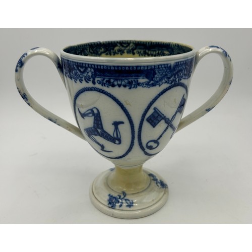 265 - An early 19th century blue and white transfer-printed loving cup, c. 1815. It has four vignettes wit... 