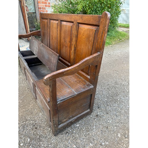 15 - A 18th/19thC oak settle with panelled back and front and lift up seats. 102 h x 152 w x 54cm d appro... 