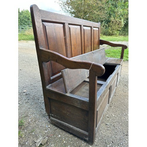 15 - A 18th/19thC oak settle with panelled back and front and lift up seats. 102 h x 152 w x 54cm d appro... 