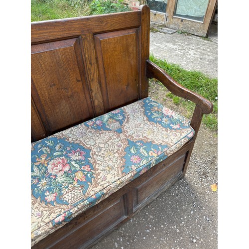 15 - A 18th/19thC oak settle with panelled back and front and lift up seats. 102 h x 152 w x 54cm d appro... 