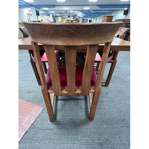 103 - An early 20thC Arts and Crafts style oak and burr walnut panels expanding dining table with eight ch... 