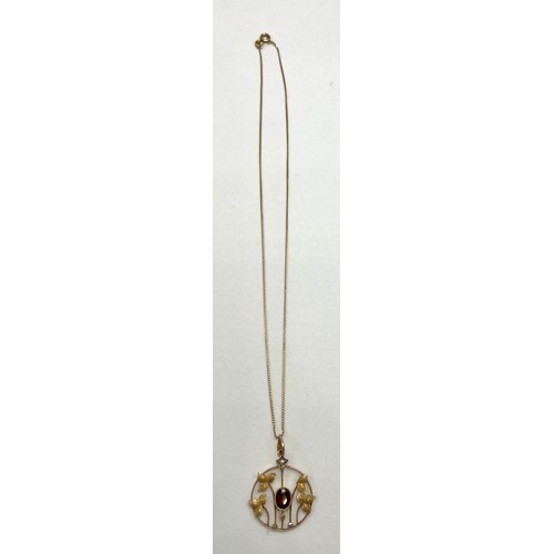 20 - A nine carat gold pendant set with central garnet and seed pearls suspended on an 18 carat gold chai... 