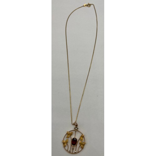 20 - A nine carat gold pendant set with central garnet and seed pearls suspended on an 18 carat gold chai... 