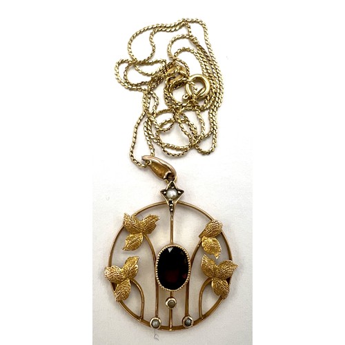 20 - A nine carat gold pendant set with central garnet and seed pearls suspended on an 18 carat gold chai... 