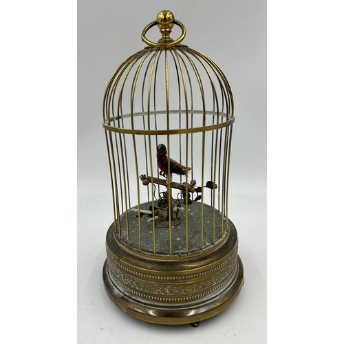 1165 - A 20thC Musical Automated Bird in a wire cage standing on a brass base edged with floral decoration.