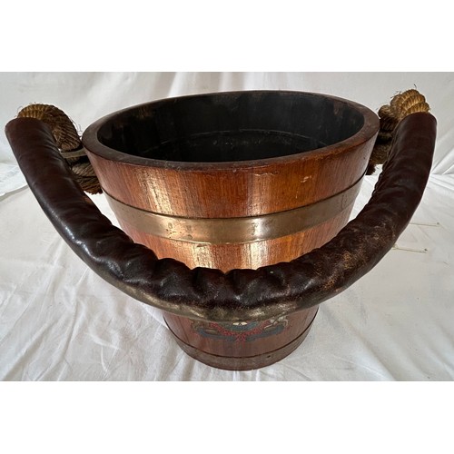 1172 - An oak naval fire bucket with insignia to the front, two copper bands and a rope handle with leather... 